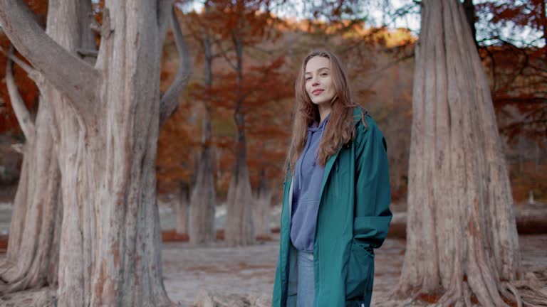 Attractive woman walking down the park and looking at the camera. Portrait of people in autumnal park. Active lifestyle.