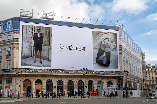 Paris, France - October 31, 2023: Yves Saint Laurent giant advertising billboard covering the scaffoldings of the restoration works on the facade of a parisian building