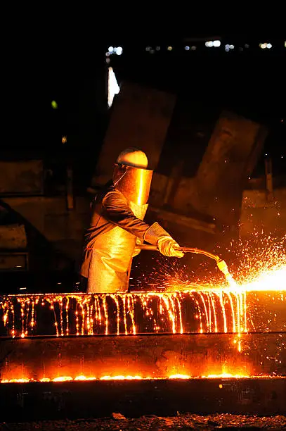 worker using torch cutter to cut through metal