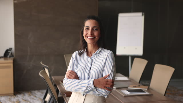 Attractive confident Brazilian businesswoman posing with arms-crossed in office