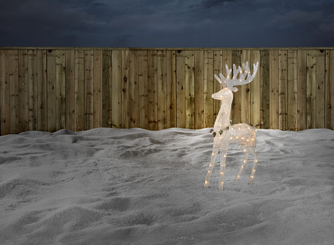 Christmas light decoration stands in a backyard covered with snow