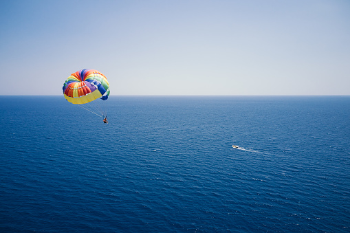 Parasailing. Aerial view of flying family with a parachute behind a boat. Extreme water sport and sea entertainment on the beach resort