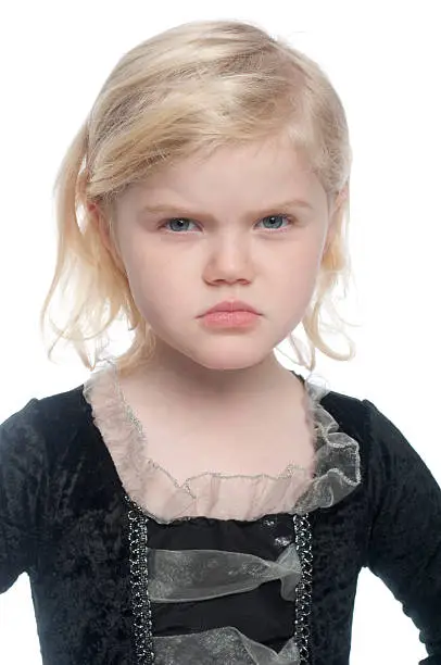 Small child has a angry expression on face. The girl is cute and has blonde hair