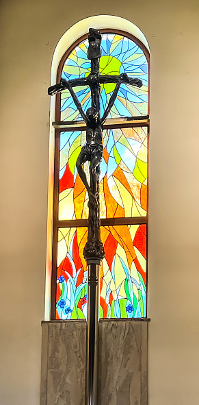 Dyrdy, Poland, October 21, 2023: Interior of the branch church of St. John Paul II in the village of Dyrdy, parish of Kalety Miotek in Poland. A papal cross and a stained glass window on the wall behind the main altar.