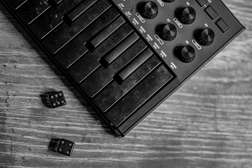 Black and white photo of a midi keyboard and dice