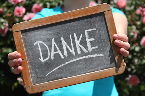 Danke (thanks in German language) written with chalk on slate shown by young female