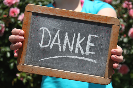 Danke (thanks in German language) written with chalk on slate shown by young female