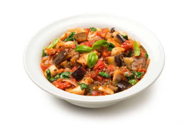 Eggplant stew with tomatoes and spinach in a salad isolated on white background. stock photo