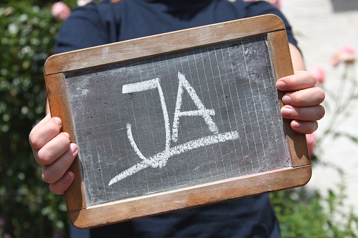 ja (yes in German language) written with chalk on slate shown by young female