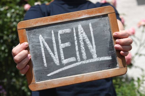 istock nein (no in German language) written with chalk on slate shown by young female 1771225938