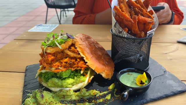 Juicy pulled chicken burger with onion rings, avocado, crispy kale, brioche bun and sweet potato french fries, food restaurant, 4K shot