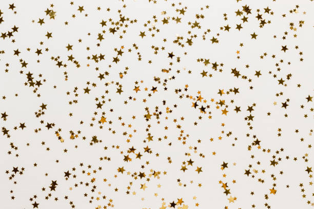 istock Golden confetti stars background on white wooden backdrop. 1771241278