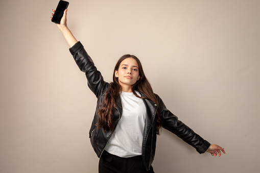 Studio portrait of a teenage girl with a mobile phone