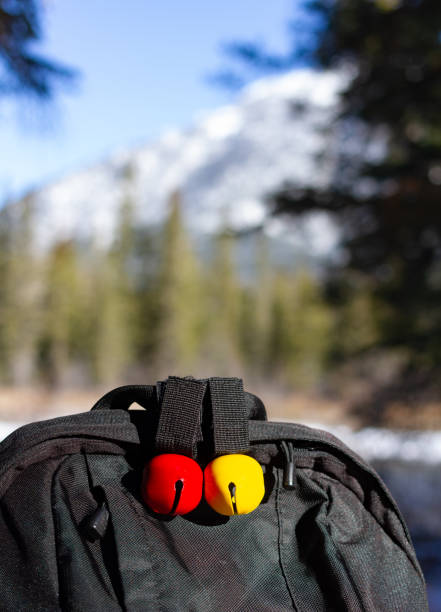 Black backpack with red and yellow bear bells, blurred winter forest and mountain background stock photo