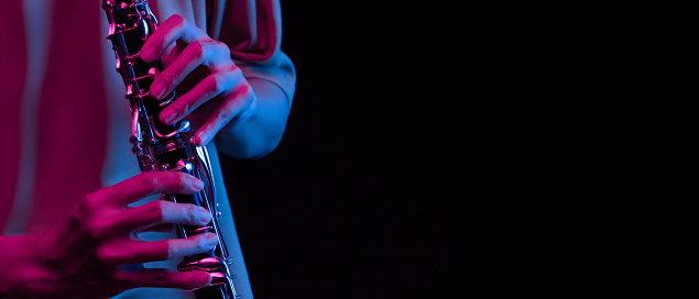 Playing the clarinet in  black background amidst the lights and sounds, a hobby in life