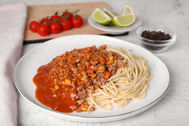 istock Tasty dish with fried minced meat, spaghetti, carrot and corn served on white textured table 1771265476