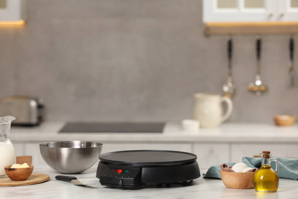 istock Electrical crepe maker and ingredients on white marble table in kitchen, space for text 1771266027