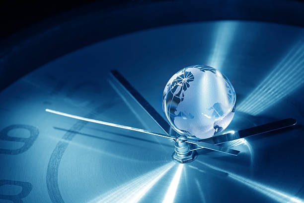 Small globe in between the hands of a clock stock photo