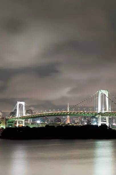 Tokyo rainbow bridge at night with Tokyo tower and city skyline in the background