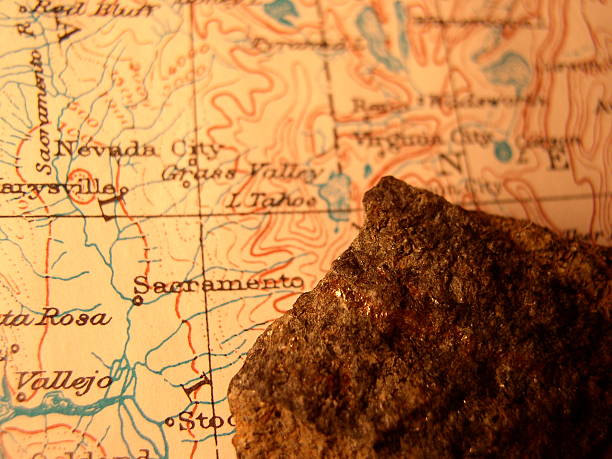 In this warm representation of the gold rush, a small piece of gold ore lies on antique map (1916-copyright free government map) of the gold rush region in California.  The bright flecks are real gold (Au) in a piece of ore from an unused gold mine. To be able to see the streak (glint of gold) means this is a rich deposit! Motivation to fortune seekers.