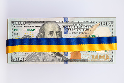 US 100 dollar banknotes with ukrainian flag colors ribbon for design purpose