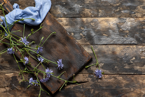 Wild chicory flowers on a wooden table. Research says that chicory is great for detoxing, especially the kidneys and liver