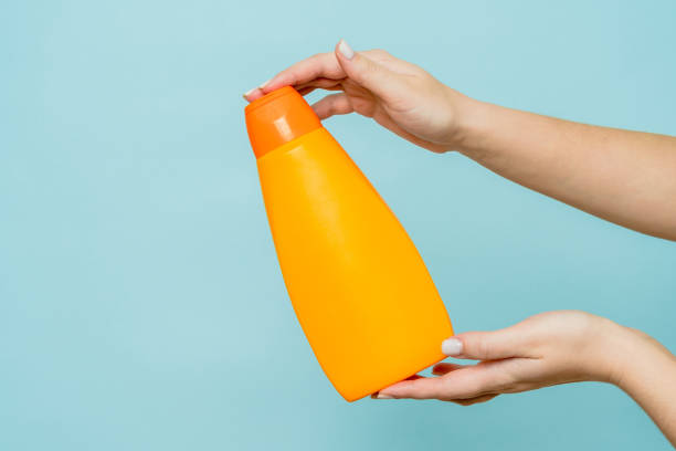istock Woman's hand holding packaging of shampoo or conditioner on blue background. Copy space and mock up 1771303935