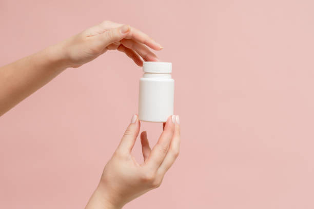 istock White bottle (plastic tube) in hands on pink background. Packaging for vitamins, pill or capsule, or supplement. Mockup for product branding 1771305617
