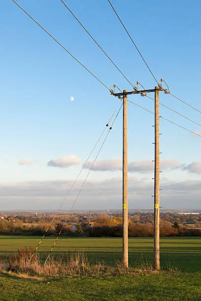 "11,000 volt (11kV), wood pole, electricity distribution line, typical of a design used across the UK.  This one is near Stratford-Upon-Avon in Warwickshire, England and was photographed on a late Autumn (Fall) evening."