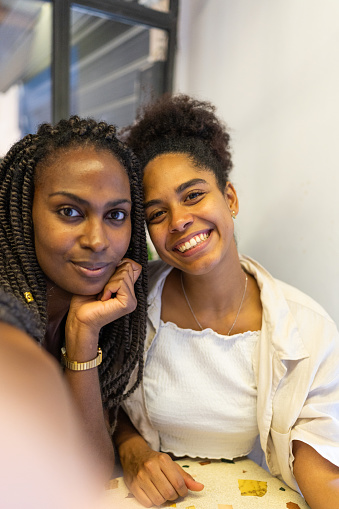 Vertical photo of two beauty african friends taking a selfie in a cafeteria