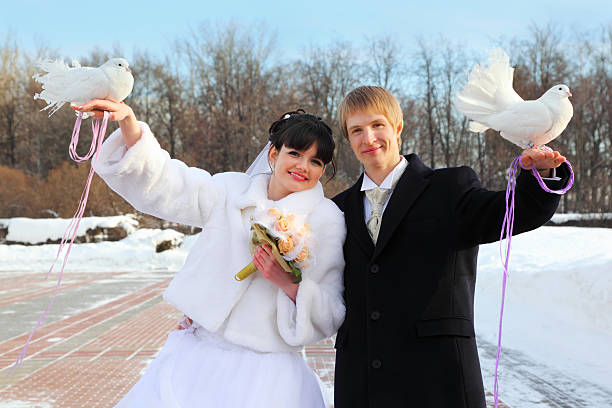 istock Smiling bride and groom hold white doves at winter 177132266