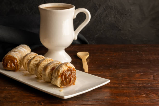 Composition of Argentine snack with cannon of dulce de leche and cup with infusion.