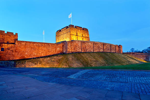 Long exposure of Carlisle (England, UK) Castle when the sun was setting. Shot in November (Late autumn in the UK). Motion blur in the flags from the long exposure. The castle has orange halogen lights that automatically switch on and light the castle through the night.