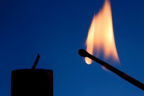 On the left side a candle without light - on the right side a burning match. Background blue.