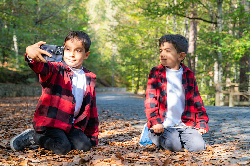 brothers having a good time together in Bolu Yedigöller National Park. During the autumn season, they can stay in touch with nature among the deciduous trees. They wore the same style of clothing. Taken in daylight with a full frame camera.