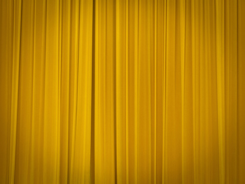 stage of the theatre with yellow curtains closed