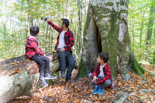 Father and sons are having a good time together in Yedigöller National Park, Bolu. During the autumn season, they can stay in touch with nature among the deciduous trees. They wore the same style of clothing. Taken in daylight with a full frame camera.