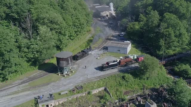 An Aerial View of an Antique Steam Locomotive Backing Up to a Water Tower to Take a Drink on a Sunny Summer Morning