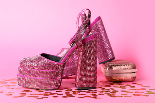 Fashionable punk square toe ankle strap pumps and confetti on pink background. Shiny party platform high heeled shoes