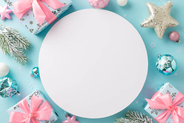 istock A sophisticated Christmas gift presentation featuring seasonal ornaments. Overhead view of baubles, gleaming star, Santa's surprises, frosted fir twigs on pastel blue backdrop, circle for text or ad 1771351468