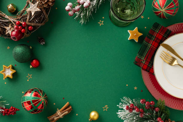 istock Festive dining setup design. Overhead view showcasing plates, cutlery, checkered napkin, wine glass, baubles, natural wreath, confetti, icy fir, mistletoe on green background, empty space for text 1771352034