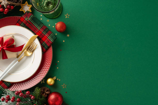 istock Christmas feast table concept. Top-view image of plates with present box, gilded flatware, checkered napkin, wine glass, baubles, glistening confetti, frosty fir, mistletoe berries with space for text 1771352035