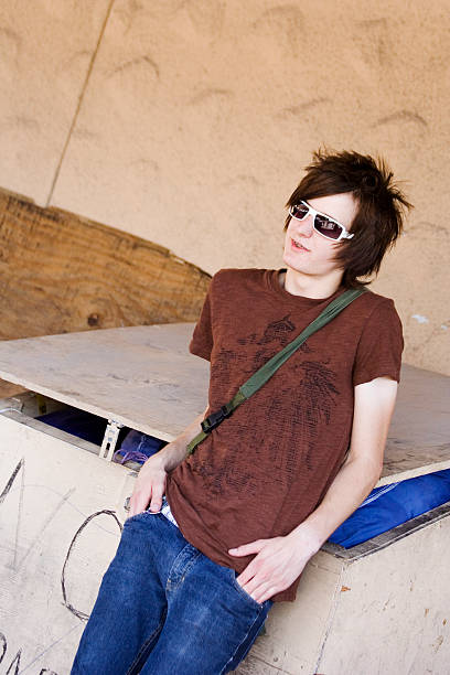 Wild teen leaning against a dumpster.