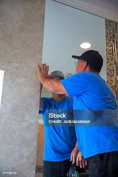 Workman Installs Mirror In Master Bathroom Stock Photo - Download Image Now - Adult, Blue, Indoors