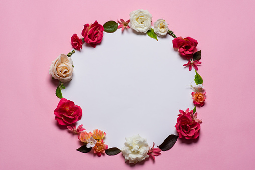 Beautifully arranged different flowers in the form of a wreath on a pink background. With space for text