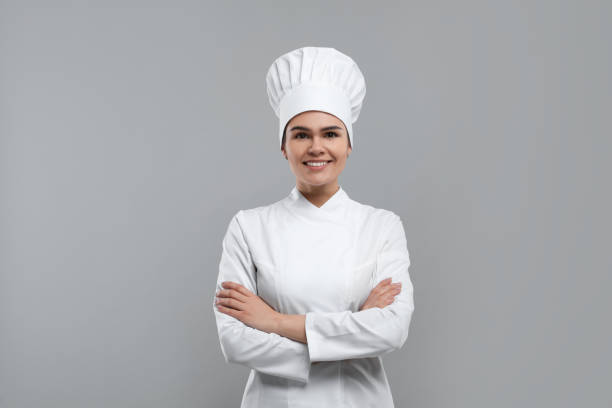 istock Happy female chef wearing uniform and cap on light grey background 1771390676