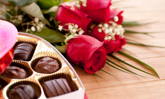 Red roses and chocolate candy on a wooden table