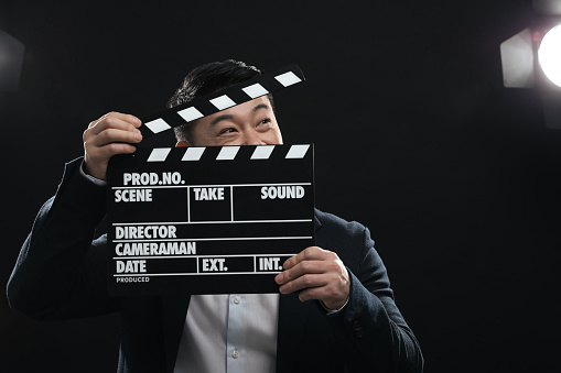 Asian actor with clapperboard on stage, space for text. Film industry