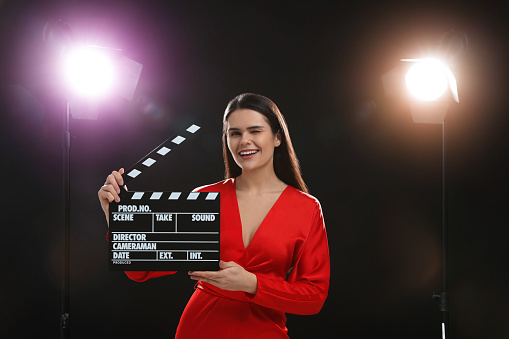 Movie production clapper board held by female’s hands against a blue background. \nCinema concept.