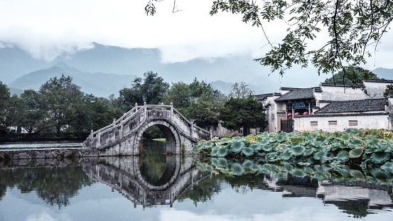 A picturesque bridge spanning across a tranquil body of water: Hongcun, China